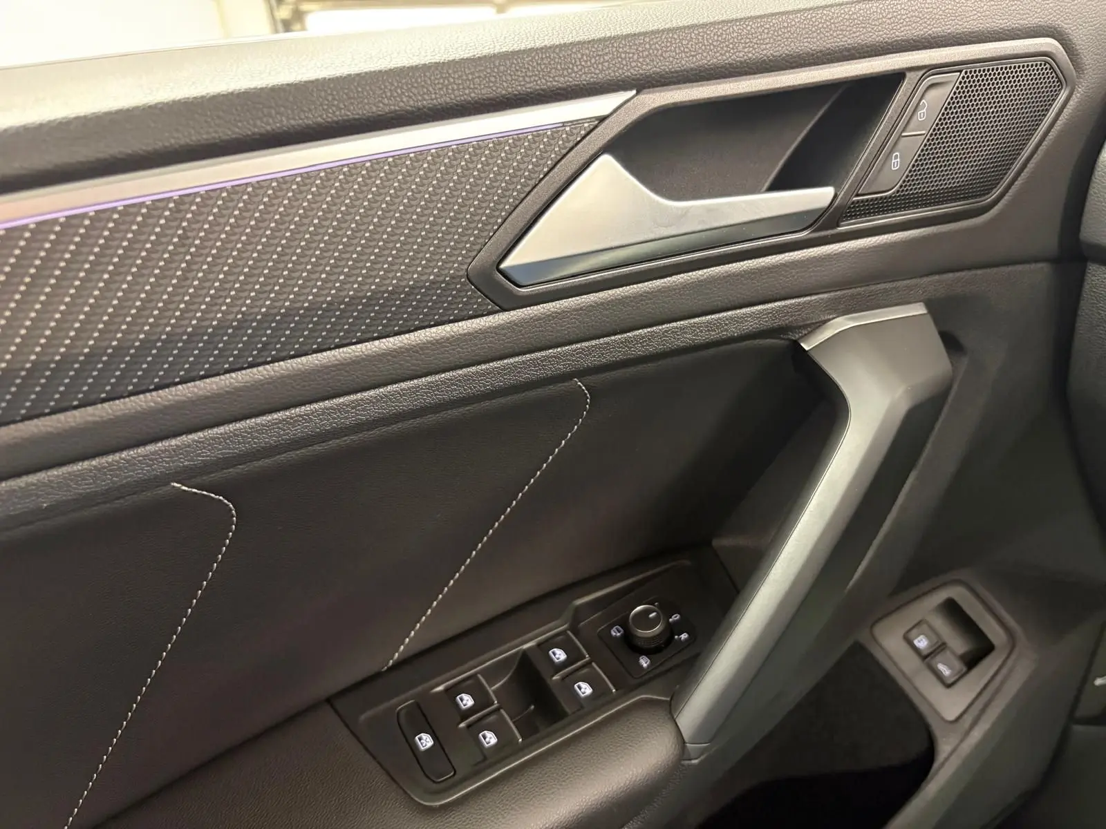 Gros plan sur la porte côté conducteur du Volkswagen Tiguan blanc pur 2023, avec commandes électriques et surpiqûres décoratives.