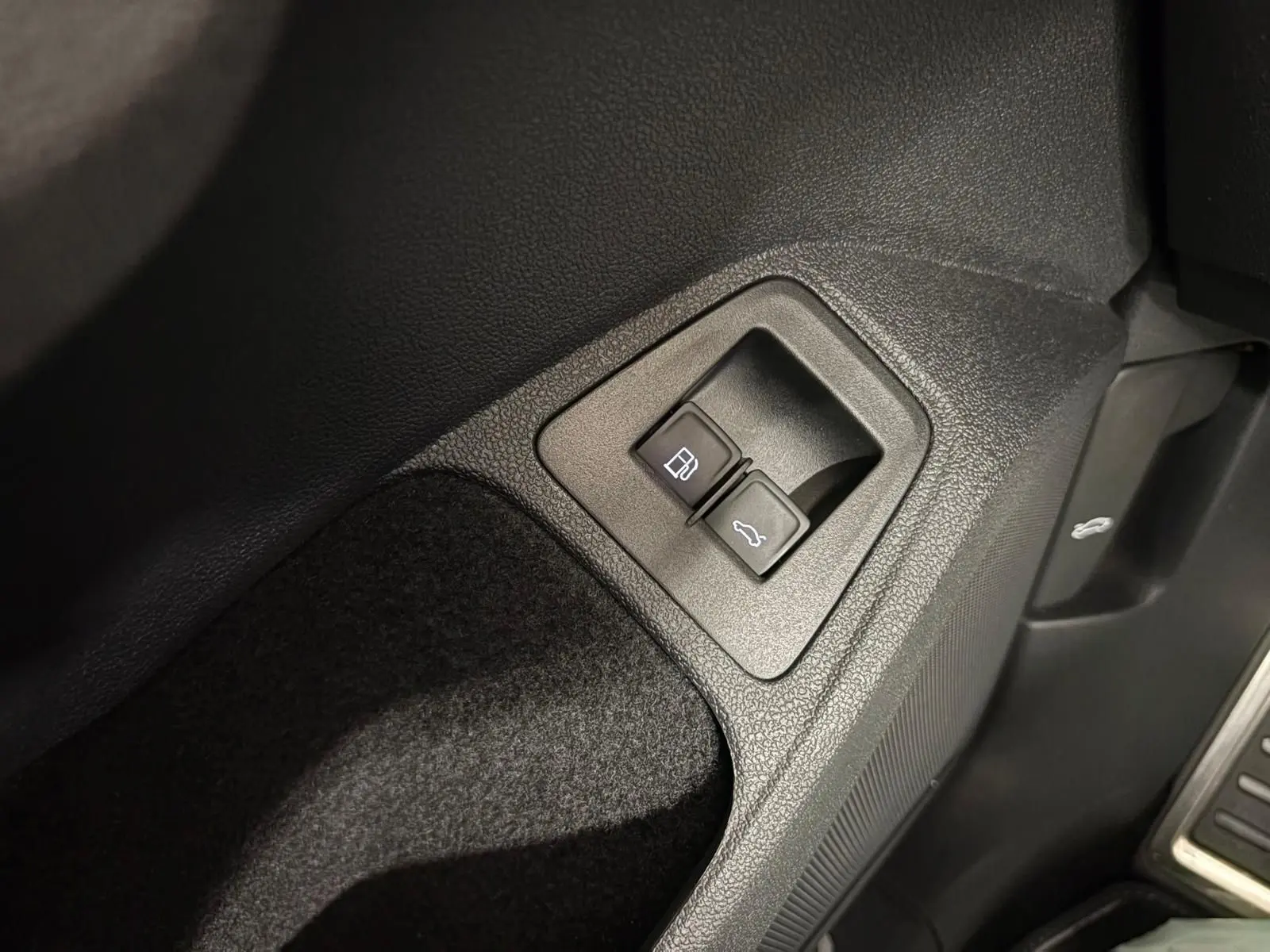 Boutons d'ouverture du réservoir et du coffre sur le côté gauche intérieur du Volkswagen Tiguan blanc 2023 R-Line Exclusive.
