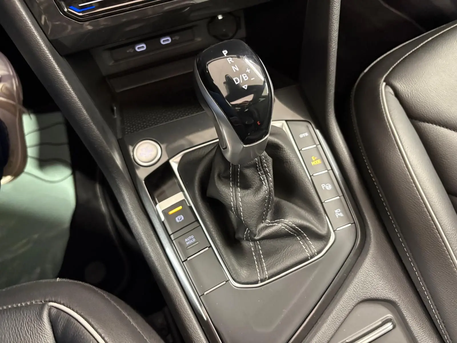 Le levier de vitesses automatique du Volkswagen Tiguan 2023 blanc pur, entouré de commandes de conduite et finition cuir noire.