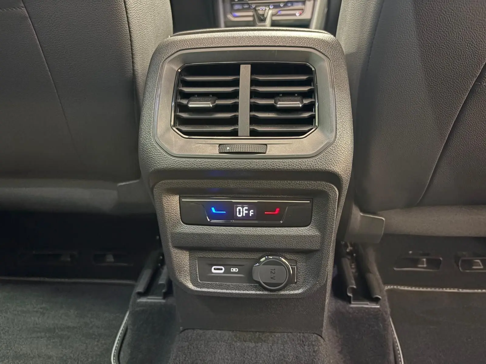 Détail de la console arrière du Volkswagen Tiguan 2023 blanc pur, avec ventilation, commandes de siège chauffant et prises USB et 12V.