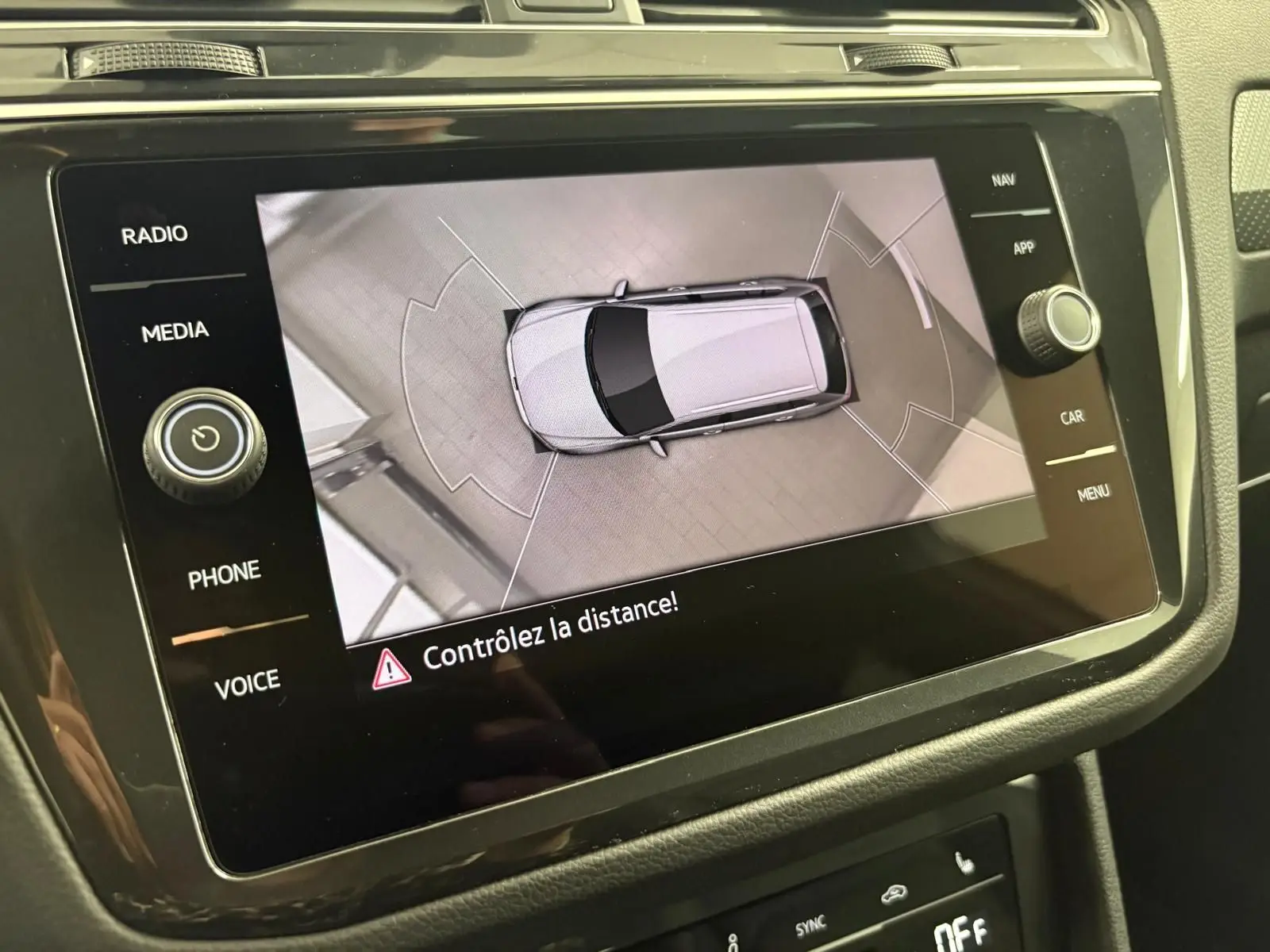 Vue aérienne du Volkswagen Tiguan blanc pur 2023 affichée sur l'écran central avec avertissement de distance.