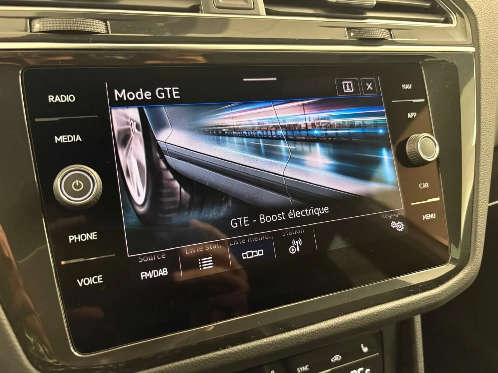 Écran tactile intérieur du Volkswagen Tiguan 2023 blanc pur affichant le mode GTE avec boost électrique en vue rapprochée.