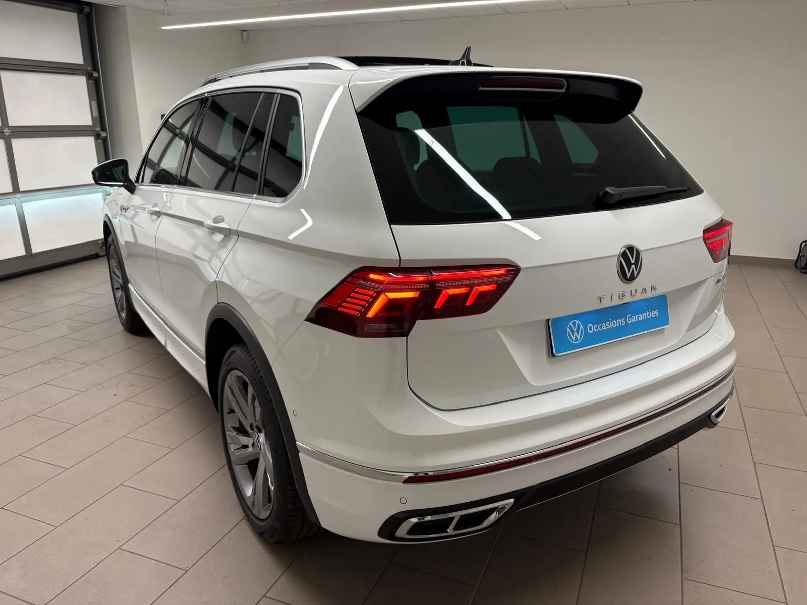 Vue 3/4 arrière gauche d'un Volkswagen Tiguan blanc pur 2023 avec feux LED et finition R-Line Exclusive.
