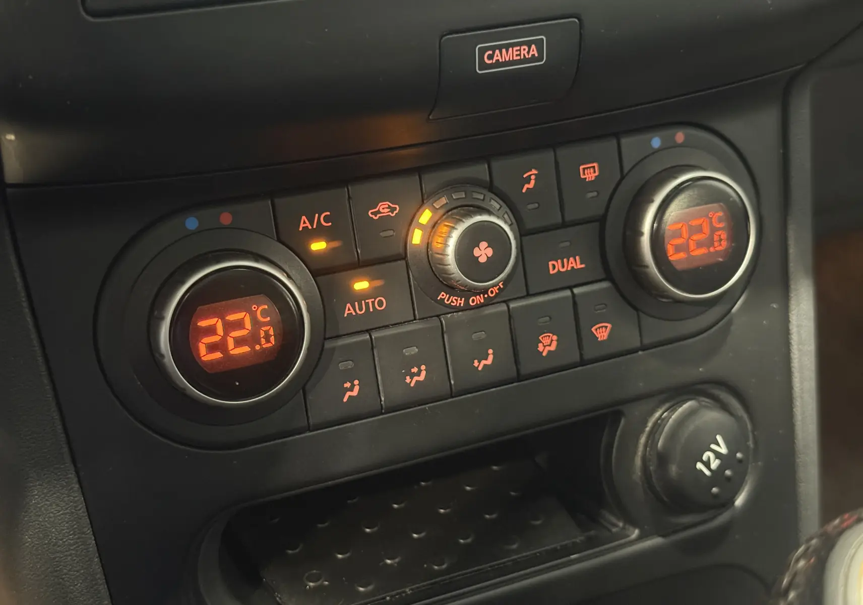 Gros plan sur la console de climatisation du Nissan Qashqai+2 gris 2014, affichant 22°C et commandes éclairées.