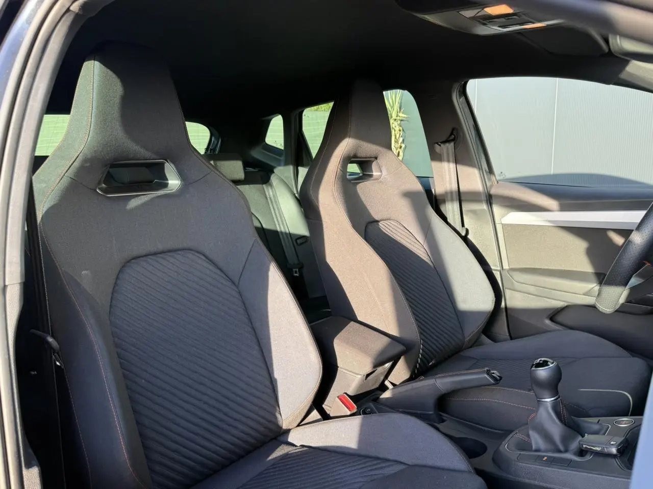 Vue intérieure côté conducteur et passager avant des sièges sport gris foncé de la SEAT IBIZA TSI 115 FR 2025 avec boîte manuelle.