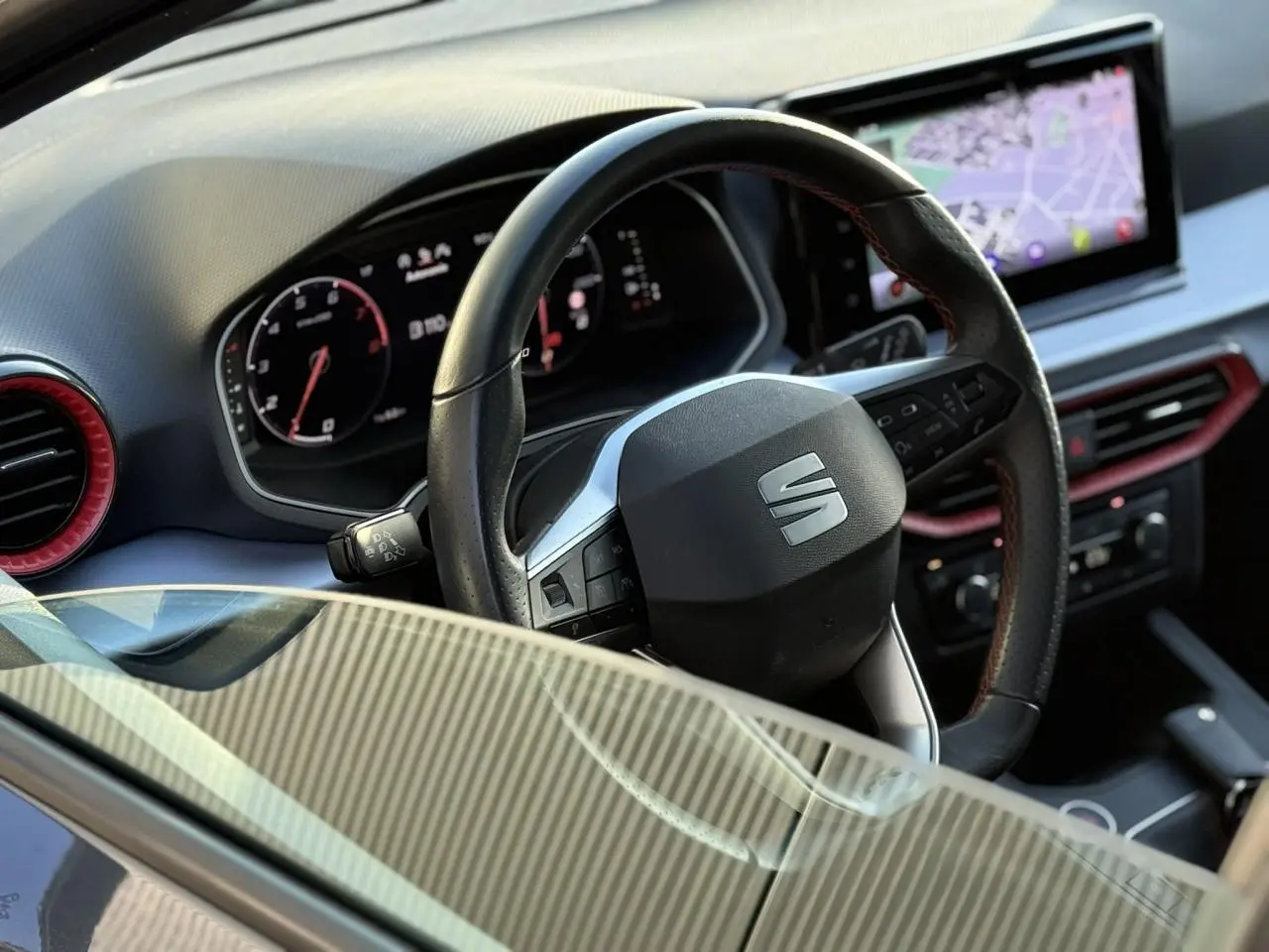 Vue intérieure rapprochée du volant noir et du tableau de bord digital avec écran de navigation d'une SEAT IBIZA 2025.