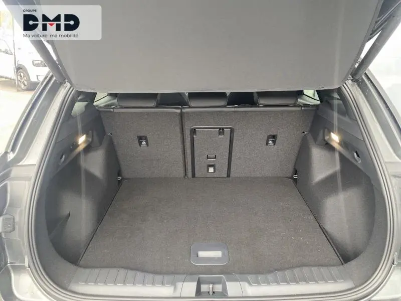 Coffre ouvert d’un Ford Explorer 2025 gris Magnetic métallisé, vue arrière avec banquette rabattable et éclairage intérieur.