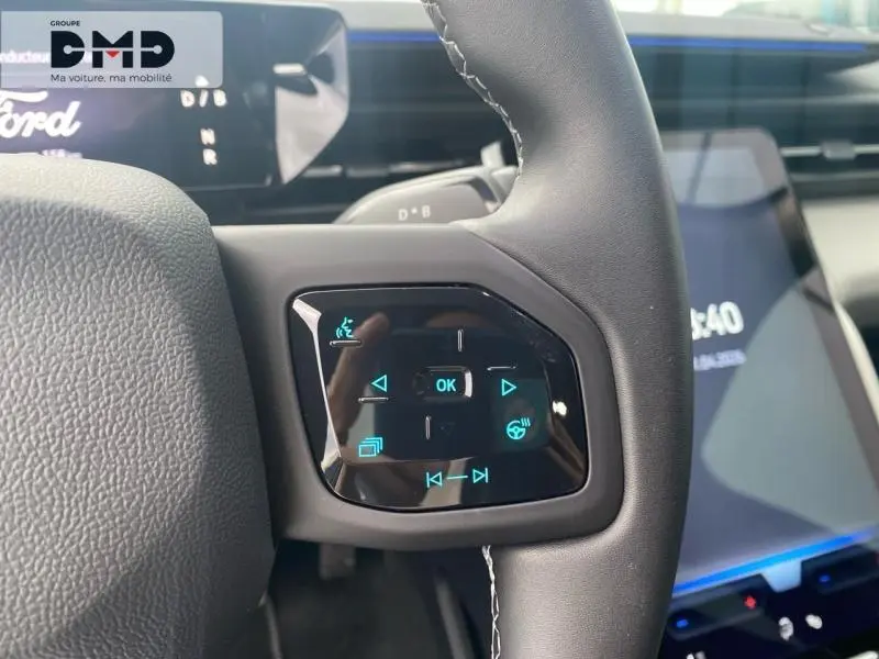 Gros plan sur les commandes tactiles bleues du volant noir du Ford Explorer 2025, intérieur moderne et écran tactile visible.