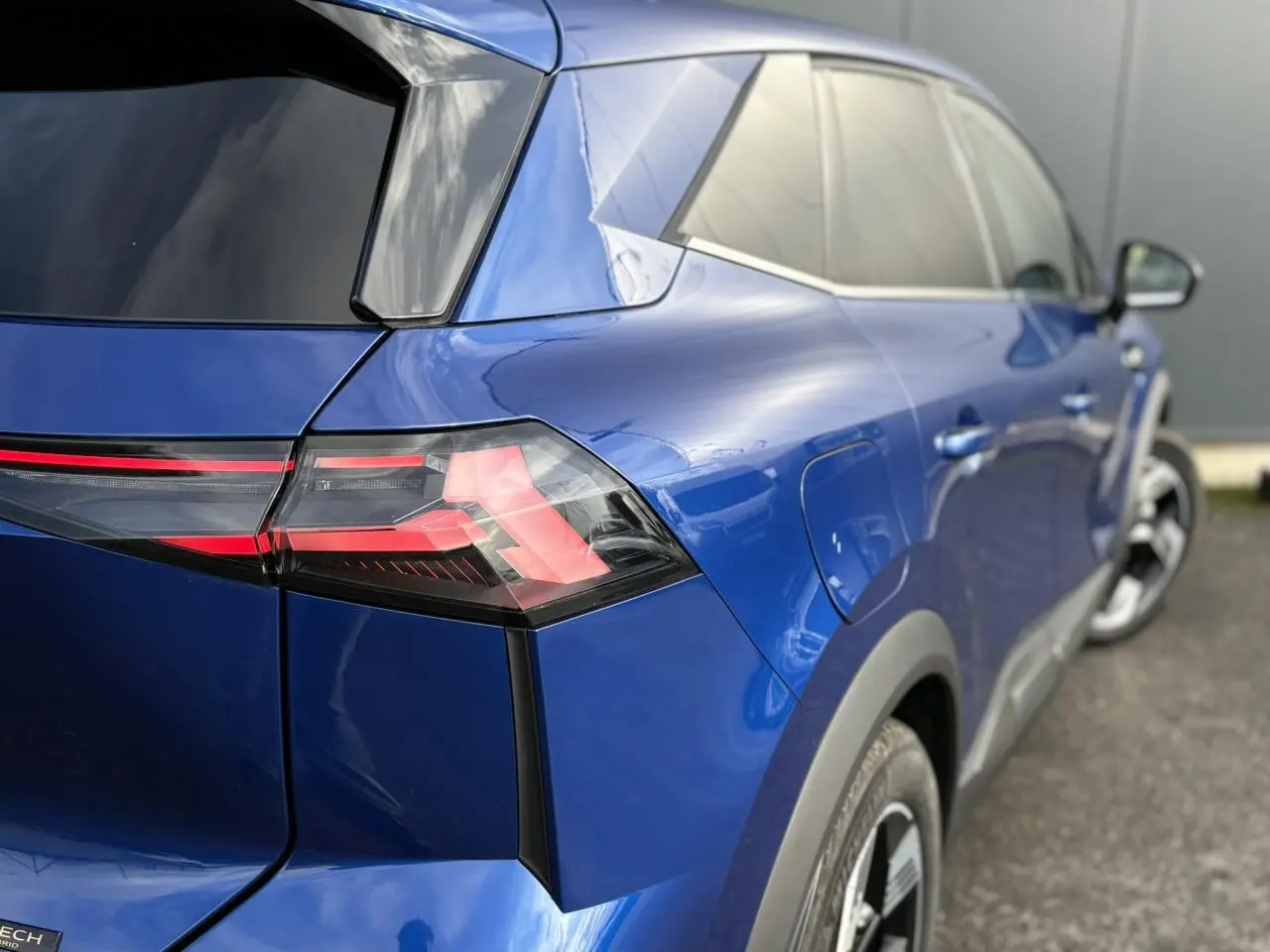 Vue 3/4 arrière droite d’un Renault Symbioz bleu Iron avec feux arrière LED et jantes 18 pouces Gravity.