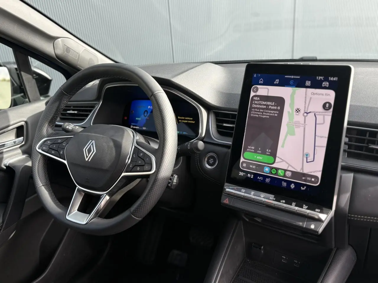 Vue intérieure du tableau de bord et volant Renault Symbioz E-Tech, écran tactile GPS vertical et commandes au volant visibles.