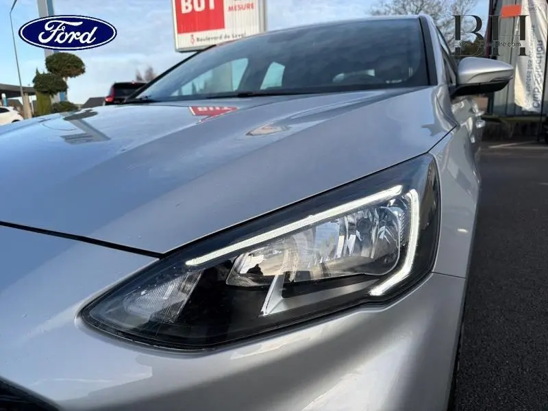 Gros plan sur le phare avant droit d'une Ford Focus gris lunaire métallisé, mettant en valeur le design LED moderne.