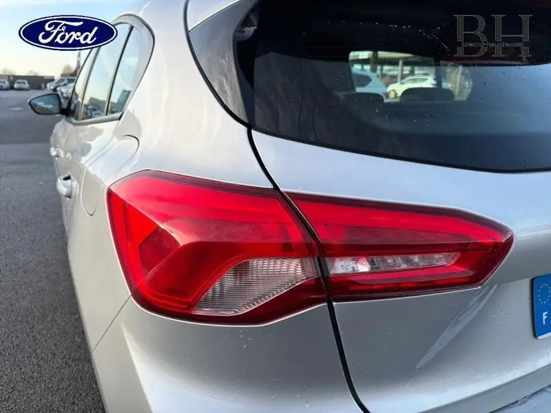 Vue arrière côté gauche d'une Ford Focus gris lunaire métallisé, mettant en valeur le feu arrière et la ligne de carrosserie.
