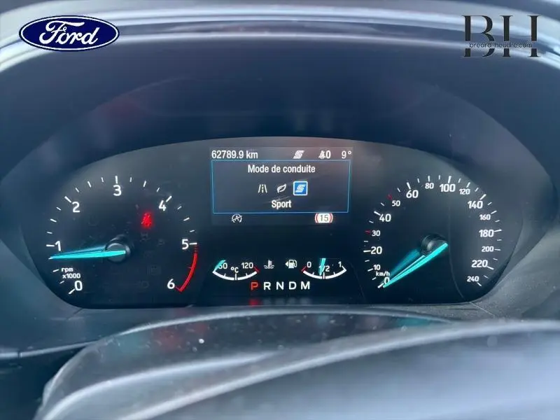 Vue rapprochée du tableau de bord numérique de la Ford Focus 1.5 EcoBlue gris lunaire, affichant le mode Sport et compteurs.