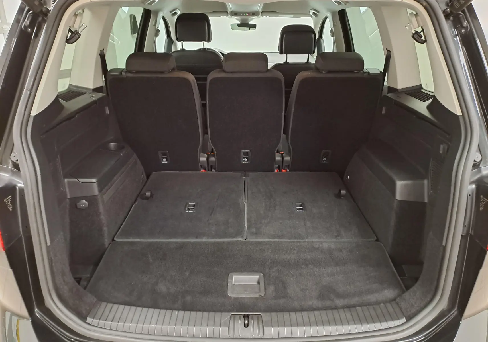 Vue arrière du coffre ouvert du Volkswagen Touran noir intense nacré, montrant les sièges arrière et l'espace de chargement.