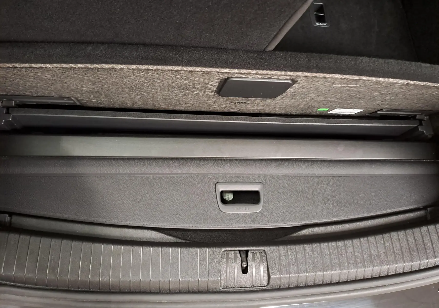 Détail du coffre arrière du Volkswagen Touran 2025 noir intense nacré, montrant la partie basse avec cache de rangement.