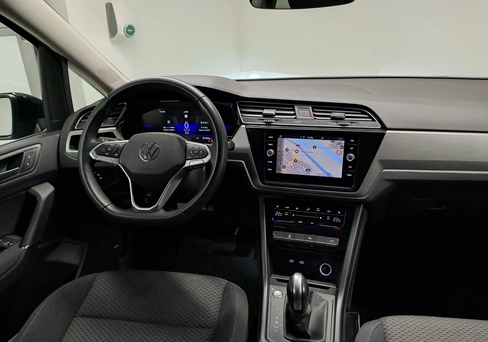 Vue intérieure du tableau de bord du Volkswagen Touran 2025, avec écran tactile et volant multifonction noir.