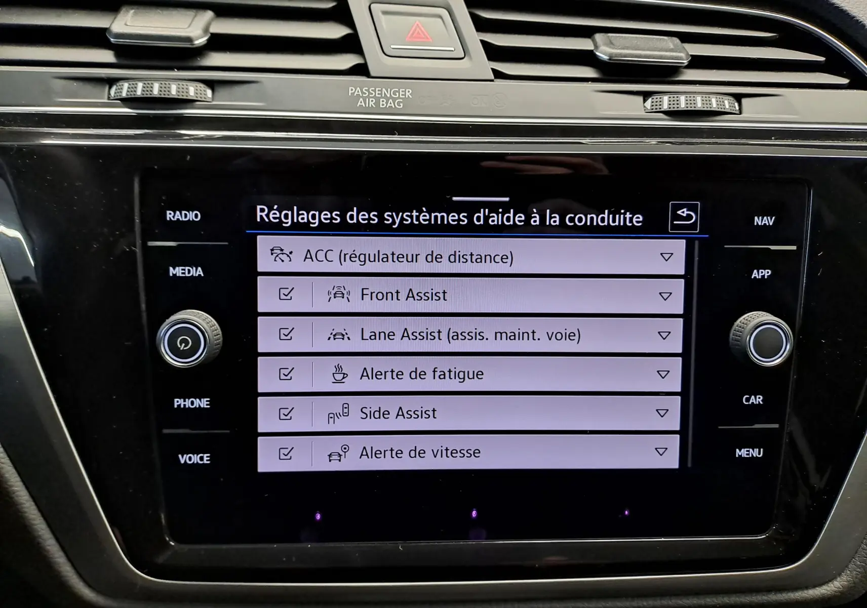 Écran tactile central du Volkswagen Touran 2025 affichant les réglages des aides à la conduite, intérieur noir.