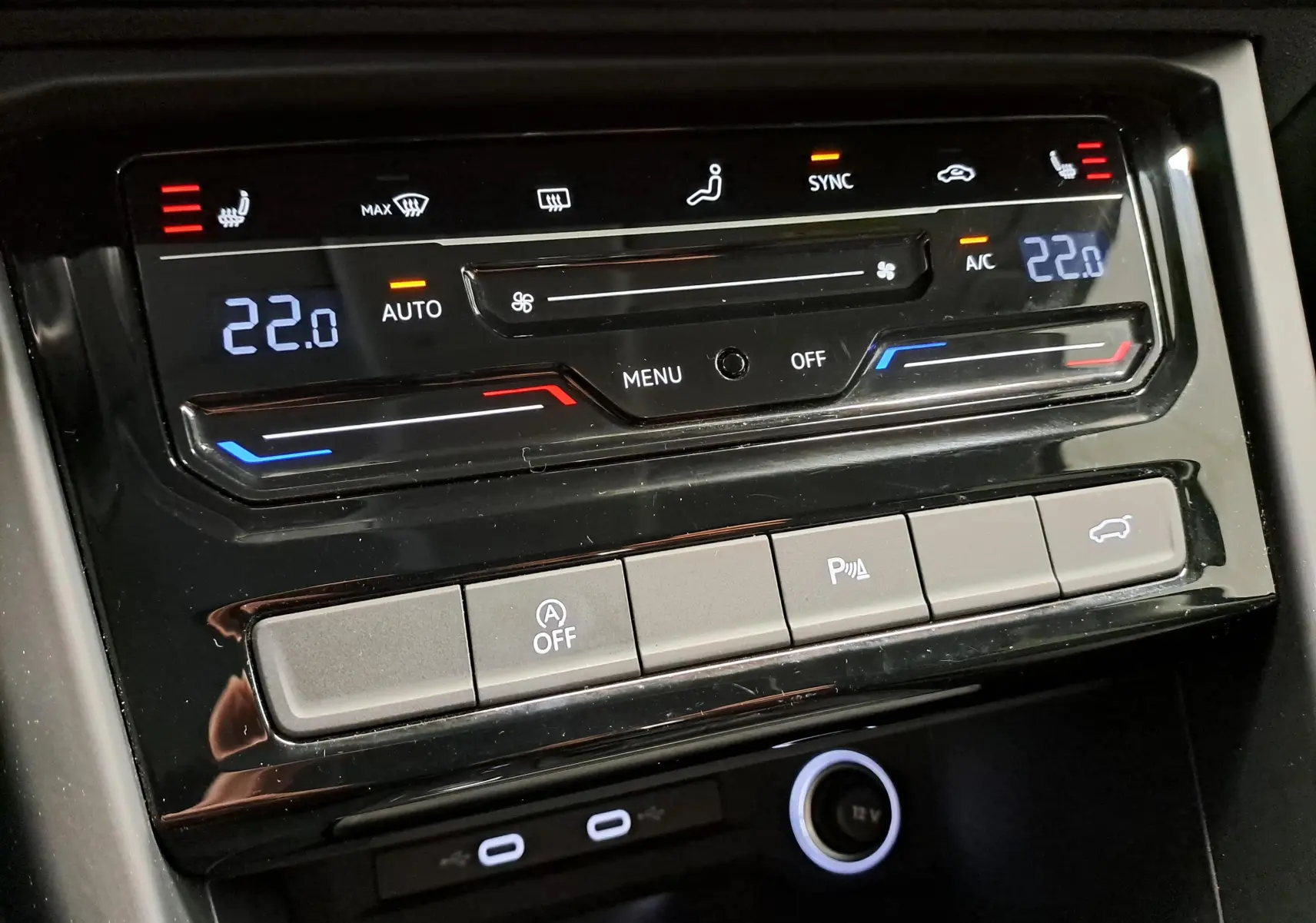 Détail de la console centrale du Volkswagen Touran 2025, affichant la climatisation digitale à 22°C et les commandes de fonctions.