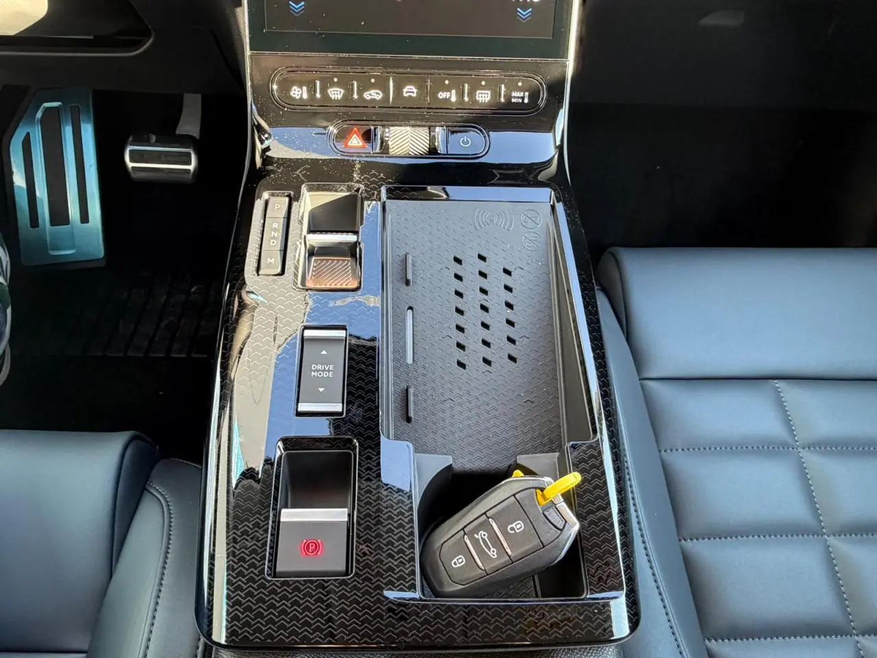 Vue rapprochée de la console centrale noire brillante du Citroën C5 Aircross avec clé et pédalier aluminium visible.