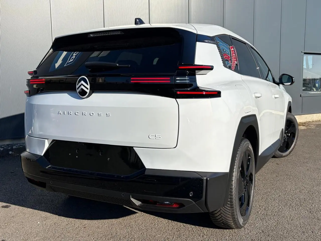 Vue 3/4 arrière droite du Citroën C5 Aircross blanc Okenite avec hayon électrique et jantes noires.
