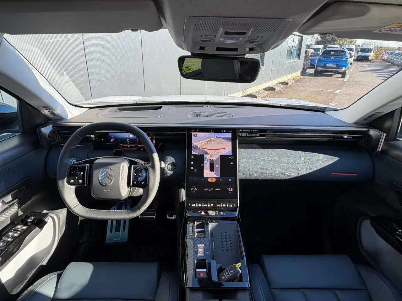 Vue intérieure avant du Citroën C5 Aircross blanc Okenite, tableau de bord moderne avec écran tactile vertical et volant multifonctions.