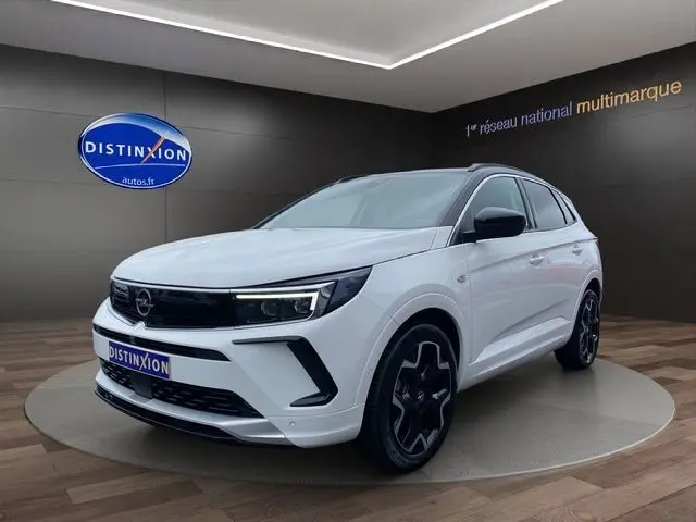 Opel Grandland blanc Arktis avec toit noir, vue 3/4 avant, jantes noires et détails noirs contrastants.