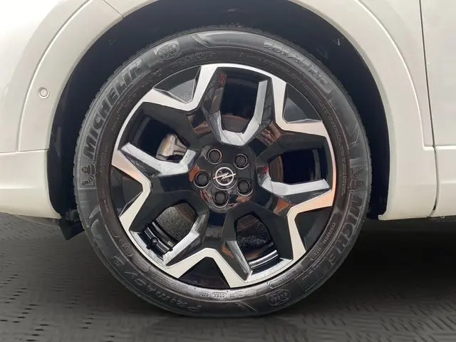 Gros plan sur la jante noire et argentée du côté gauche d’un Opel Grandland blanc Arktis avec toit noir.