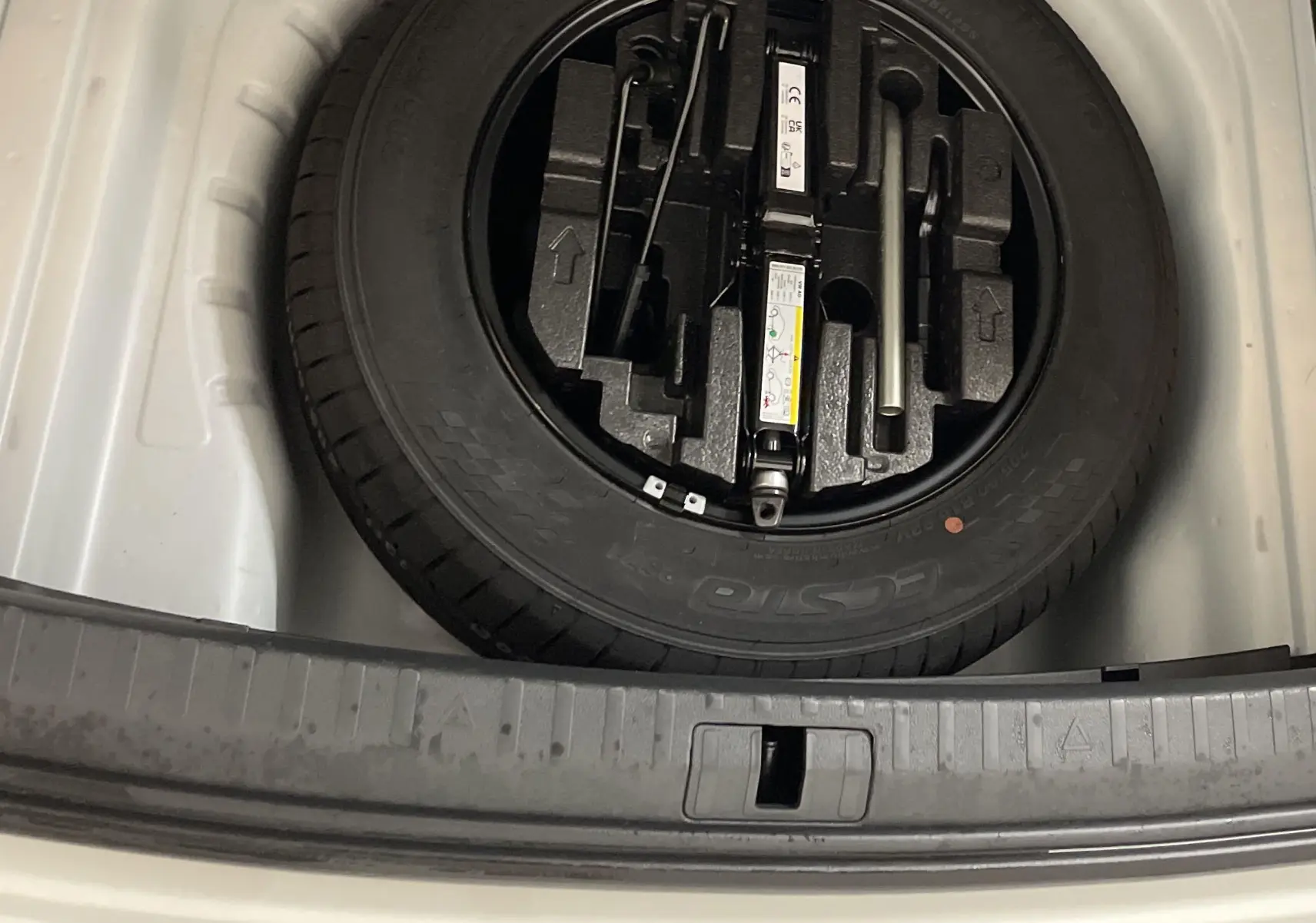 Gros plan sur la roue de secours galette noire dans le coffre blanc d’une Skoda Octavia 2024 2.0 TDI DSG7.