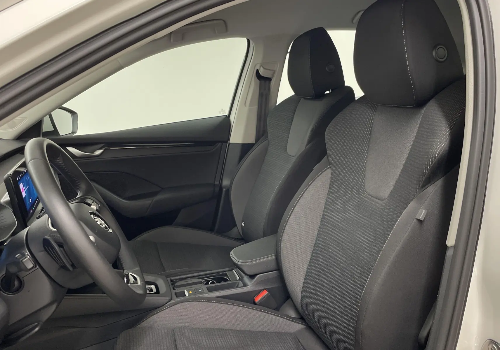 Intérieur de la Skoda Octavia 2024 blanc candy, vue côté gauche montrant sièges avant et tableau de bord moderne.