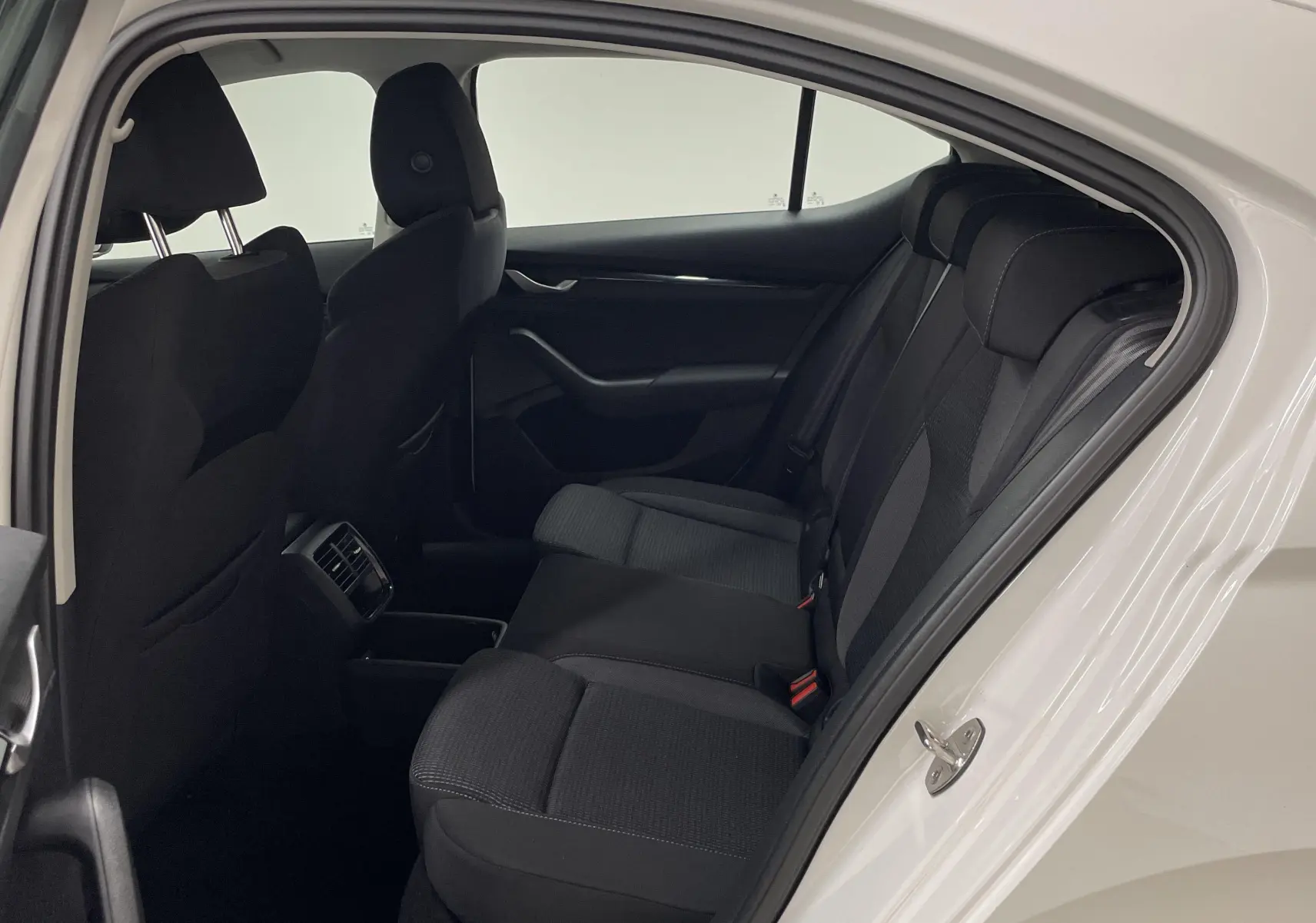 Vue intérieure côté droit arrière de la Skoda Octavia 2024 blanc candy, montrant les sièges arrière noirs et la portière ouverte.