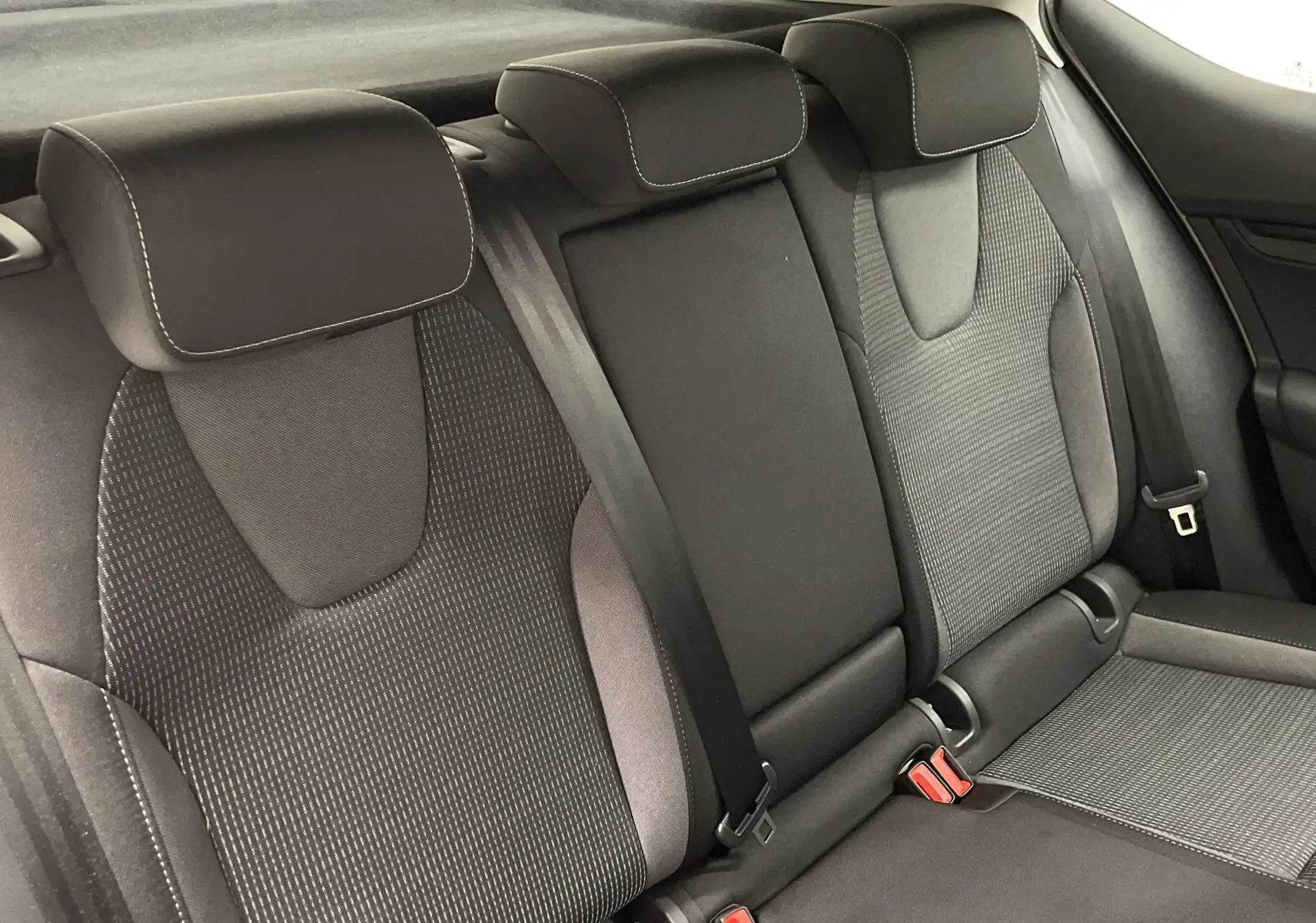 Vue rapprochée des sièges arrière noirs et gris de la Skoda Octavia 2024, finition Selection, avec ceintures visibles.