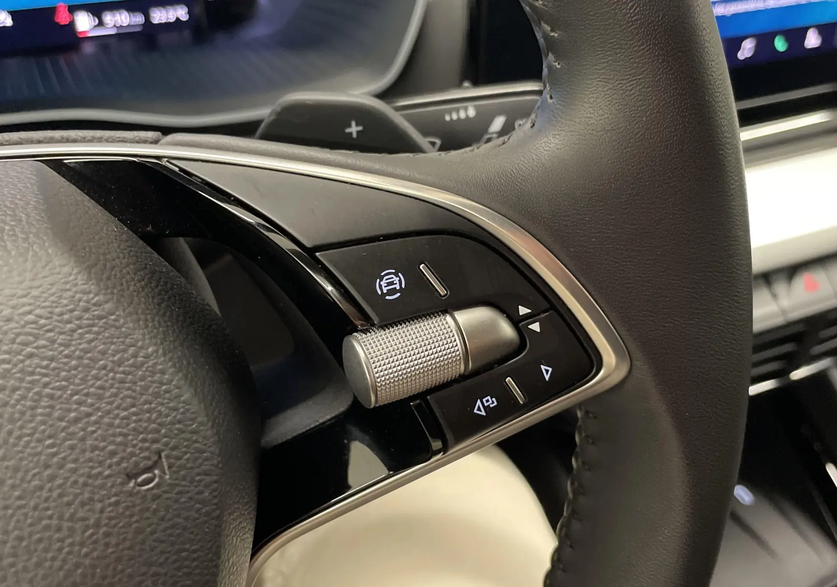 Gros plan sur les commandes à droite du volant en cuir noir du Skoda Octavia 2024, avec molette texturée et affichage digital en arrière-plan.