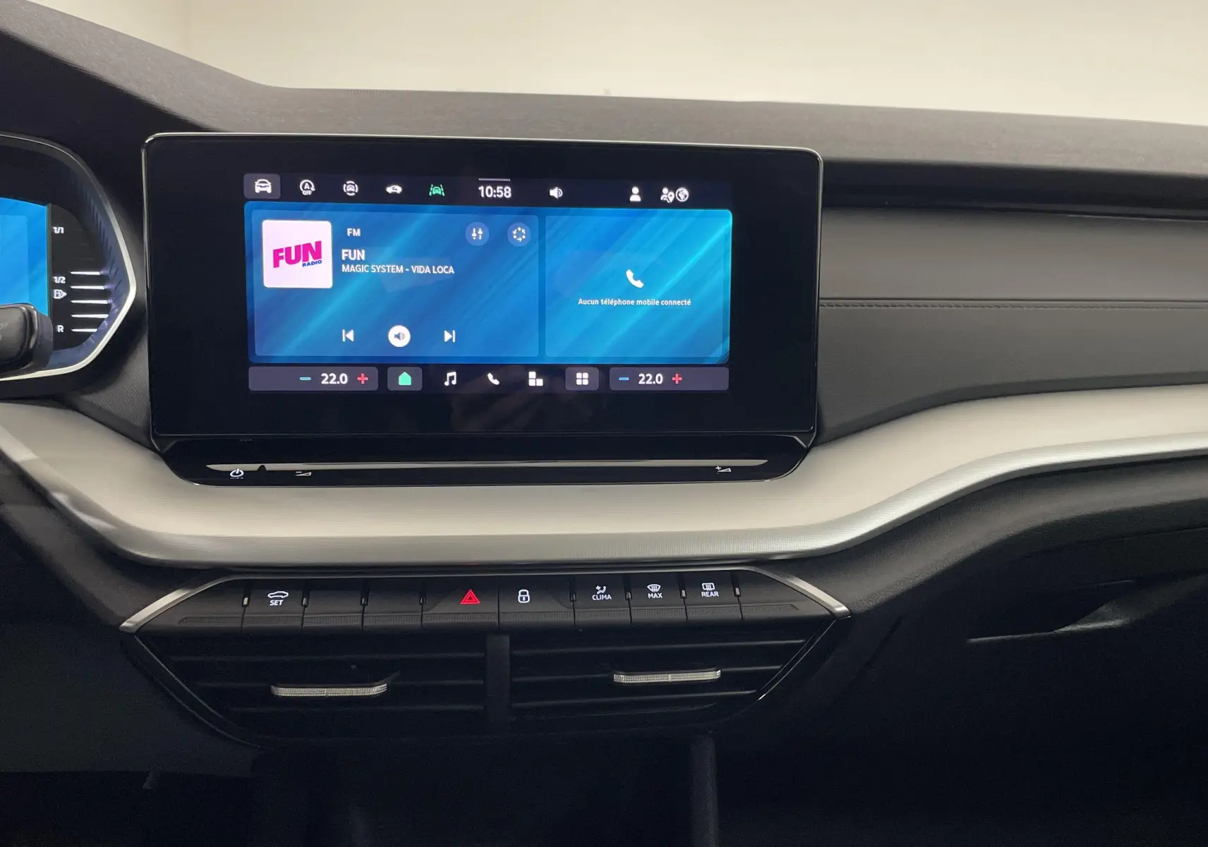 Tableau de bord intérieur de la Skoda Octavia 2024, écran tactile central allumé avec interface radio et climatisation.