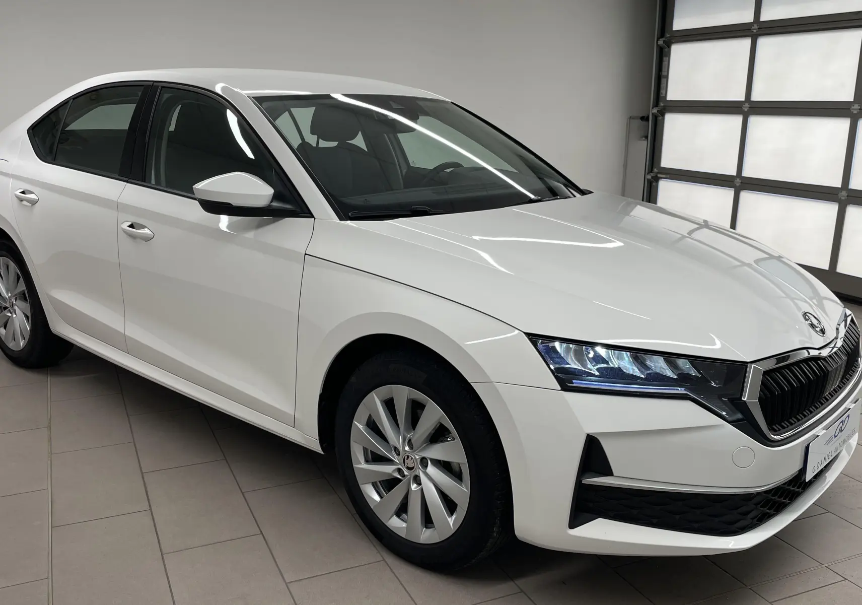 Skoda Octavia 2024 blanc candy vue 3/4 avant droit, phares LED allumés et jantes alliage multibranches.