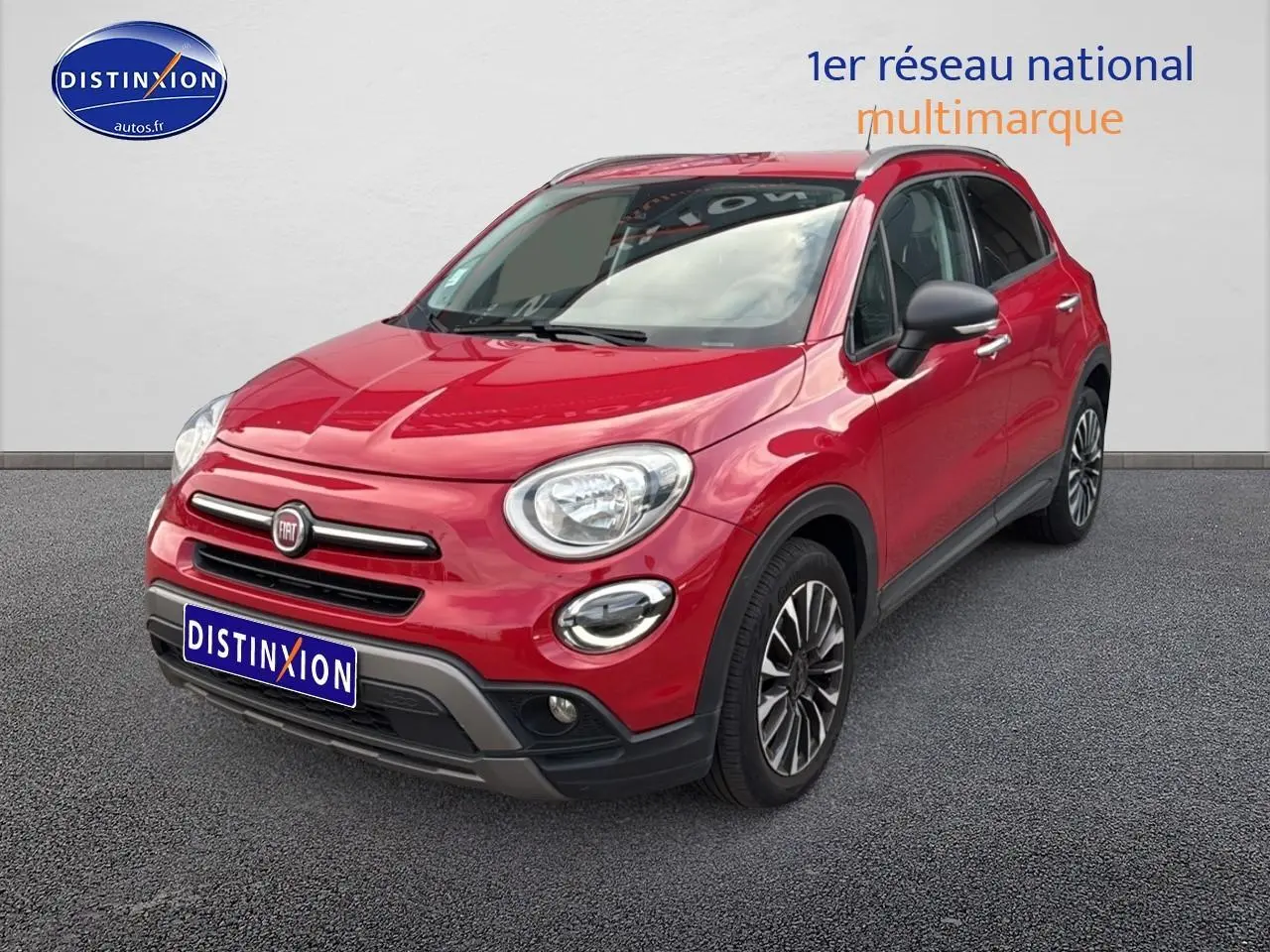 Fiat 500X rouge vue 3/4 avant droit sur sol gris avec jantes alliage et calandre chromée.
