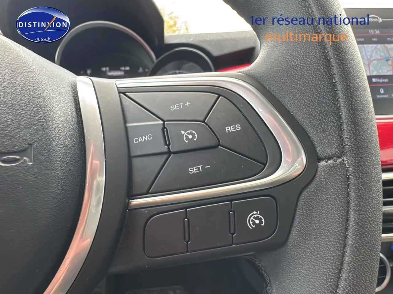 Gros plan sur les commandes du régulateur de vitesse au volant cuir noir de la FIAT 500X rouge 2020.