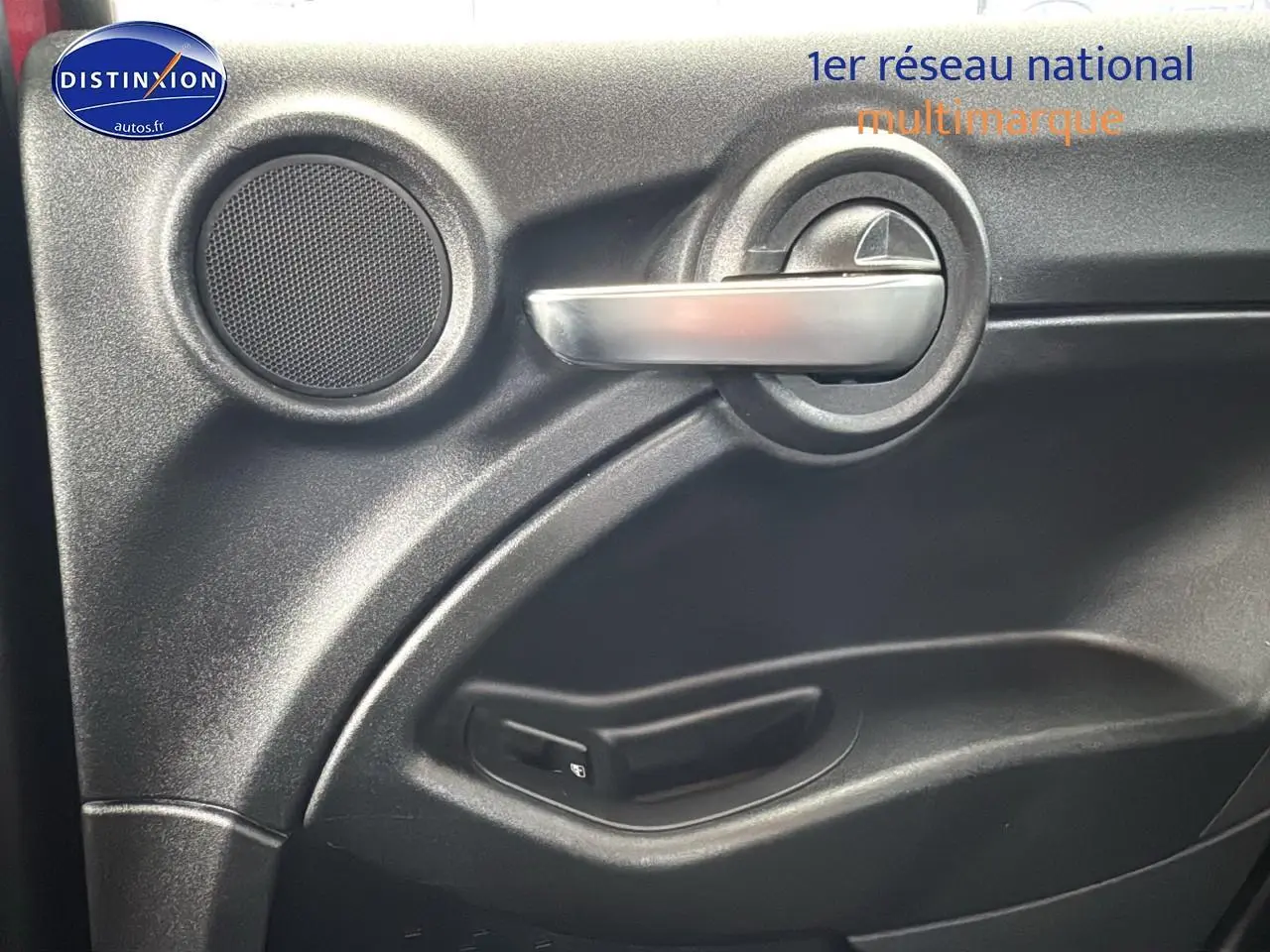 Poignée intérieure argentée et haut-parleur sur la porte côté conducteur d'une FIAT 500X rouge 2020.