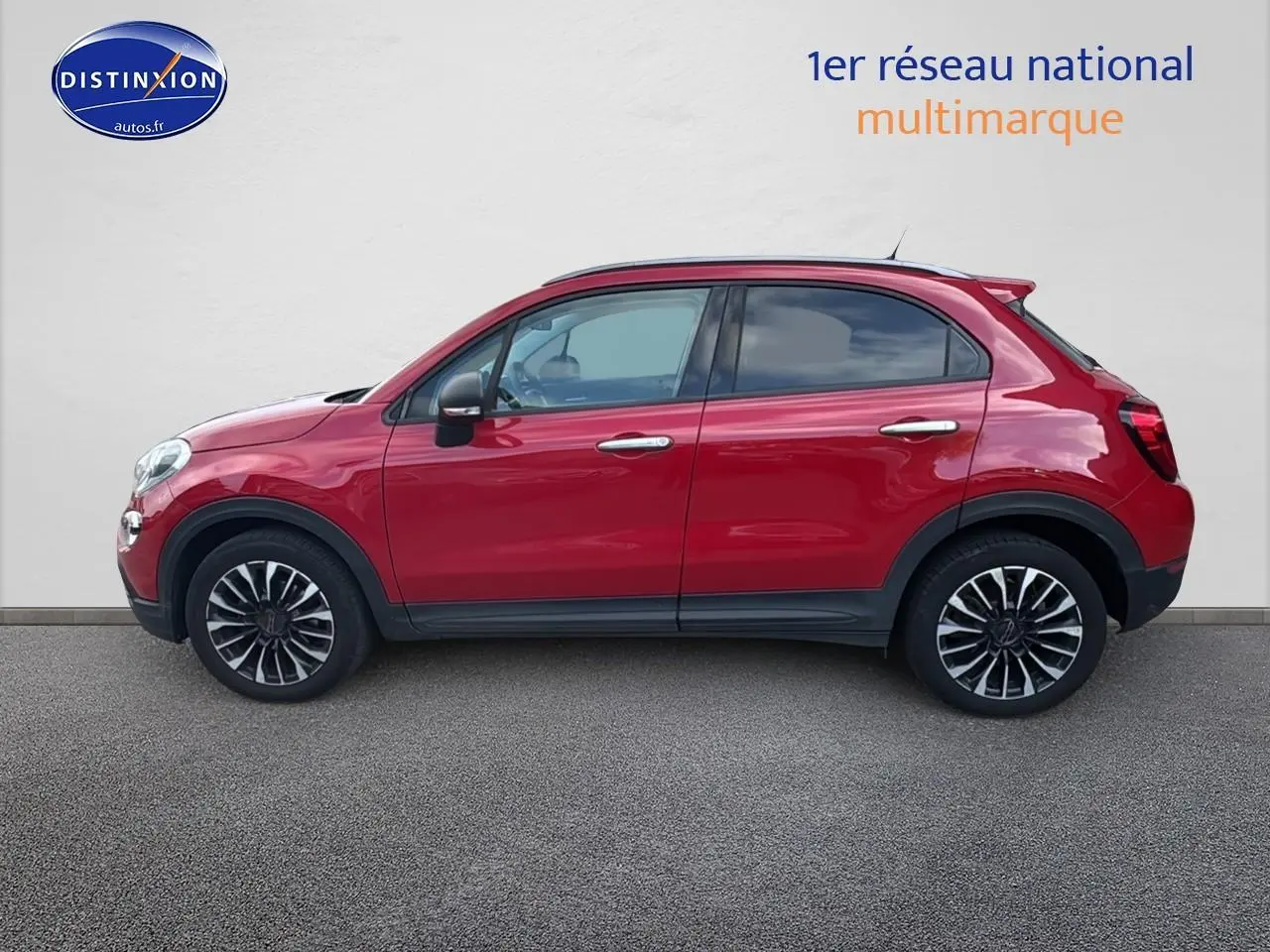 Profil côté gauche d'un FIAT 500X rouge 2020 avec jantes alliage et poignées chromées sur fond neutre.