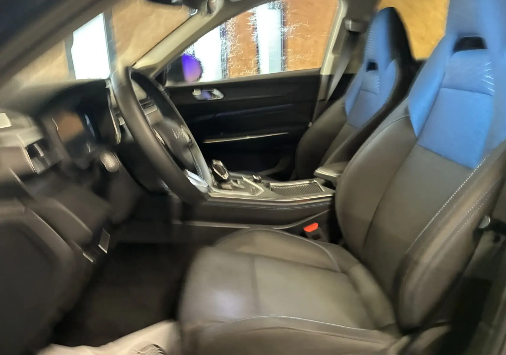 Vue intérieure côté conducteur du Lynk & Co 01 2023 avec sièges en cuir noir et bleu et console centrale moderne.