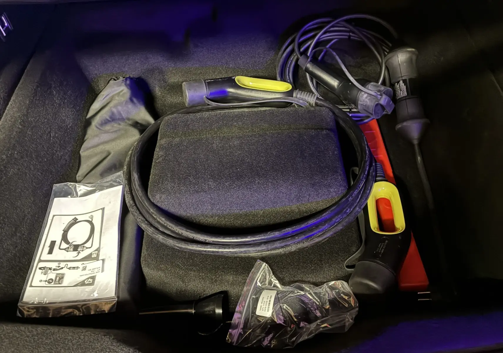 Coffre du Lynk & Co 01 bleu 2023 montrant câble de recharge hybride et accessoires de charge rangés.