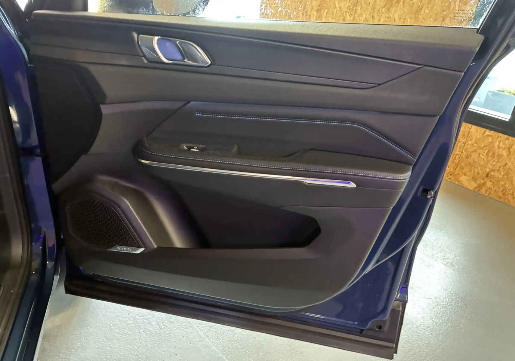 Vue rapprochée de la porte avant gauche bleu du Lynk & Co 01 avec garniture noire et surpiqûres bleues.