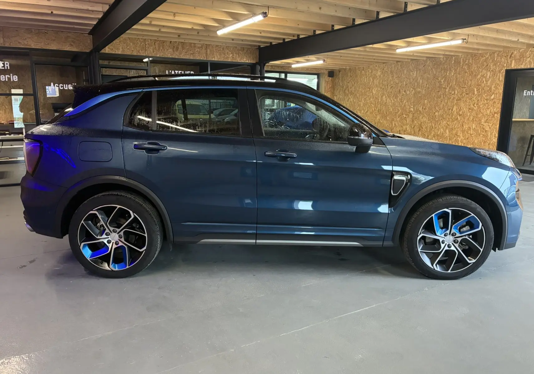 Vue latérale droite du SUV LYNK & CO 01 hybride rechargeable bleu, avec jantes sport et détails noirs contrastants.