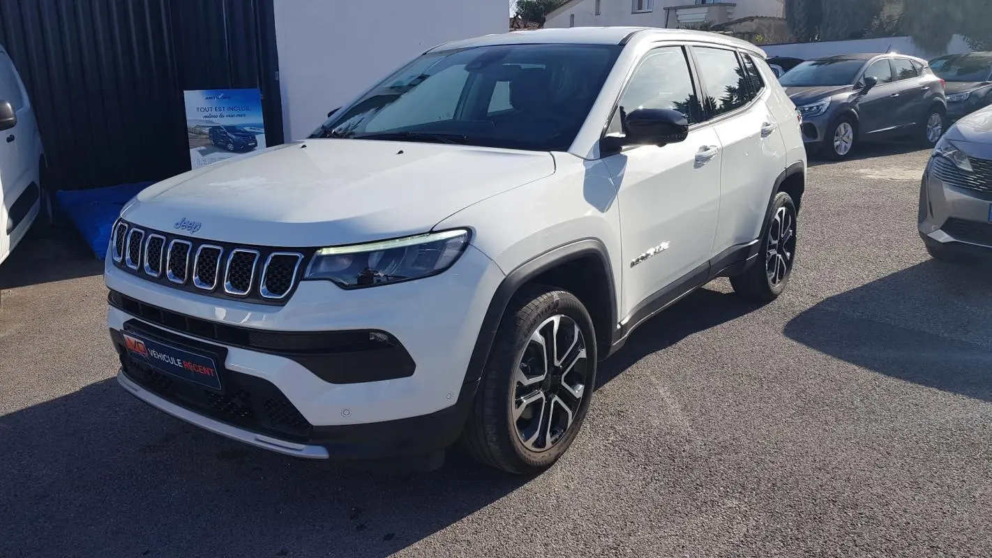 Jeep Compass blanc vu en 3/4 avant droit, avec jantes alliage noires et calandre distinctive à sept fentes.