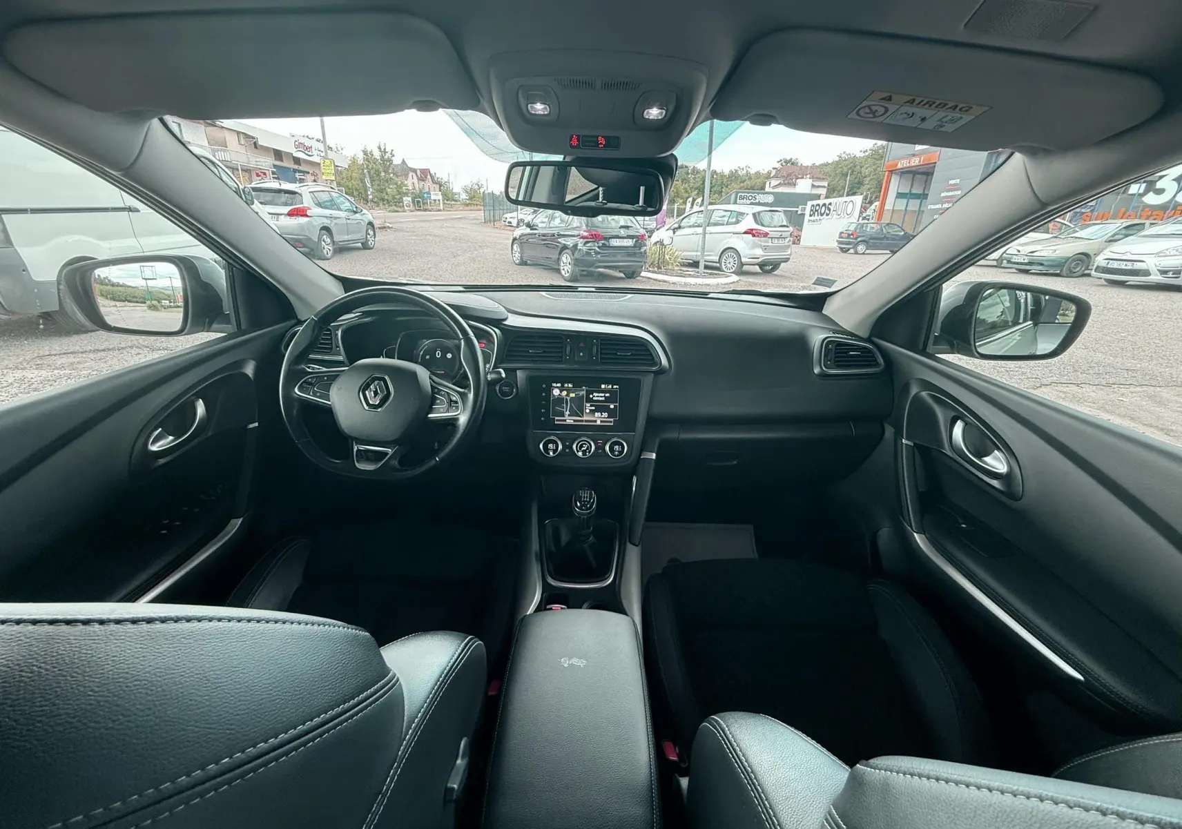 Vue intérieure avant du Renault Kadjar 2020, tableau de bord noir avec volant multifonction et boîte manuelle.