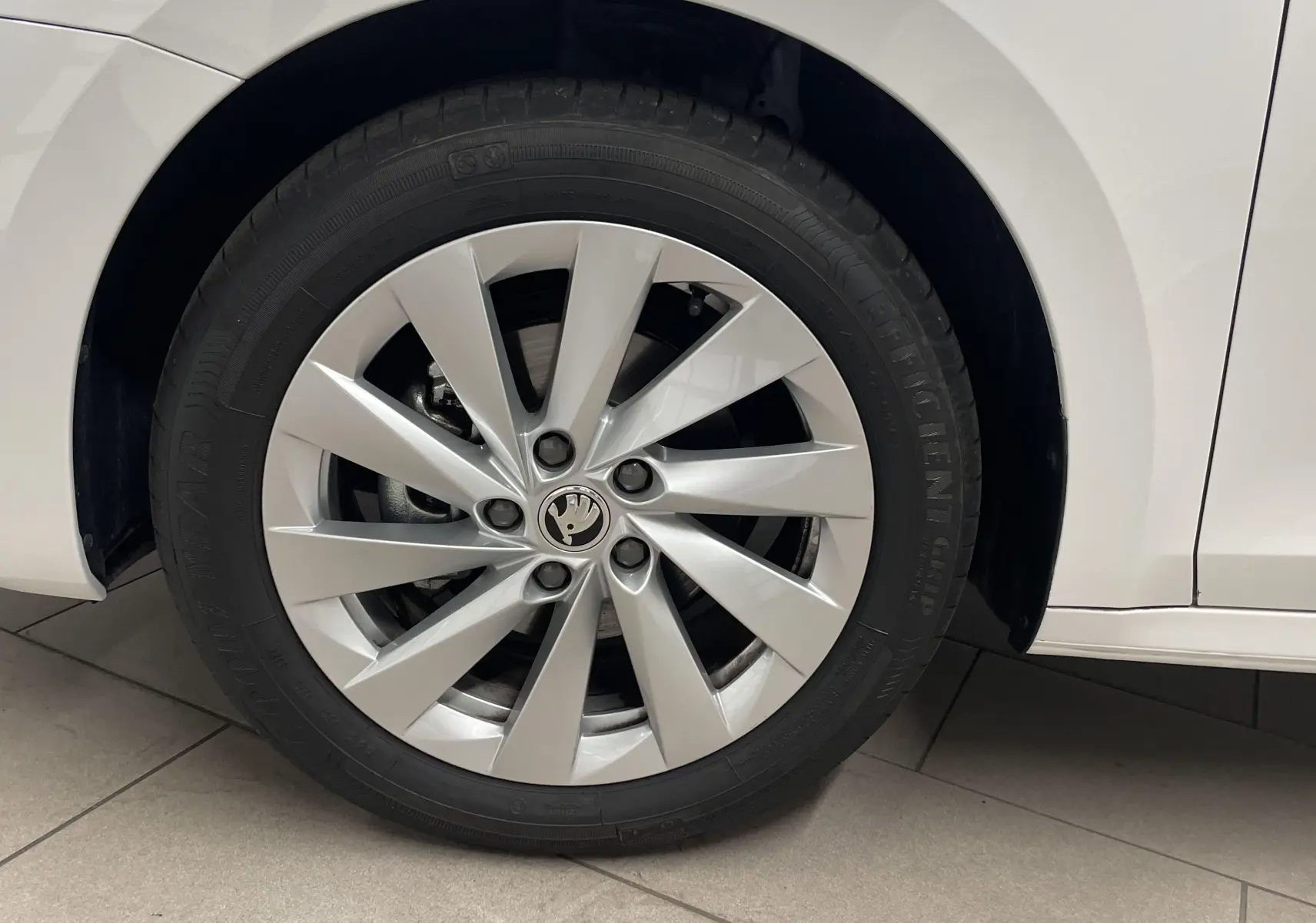 Gros plan sur la roue avant gauche blanche d'une Skoda Octavia 2024 avec jante argentée et pneu Goodyear.