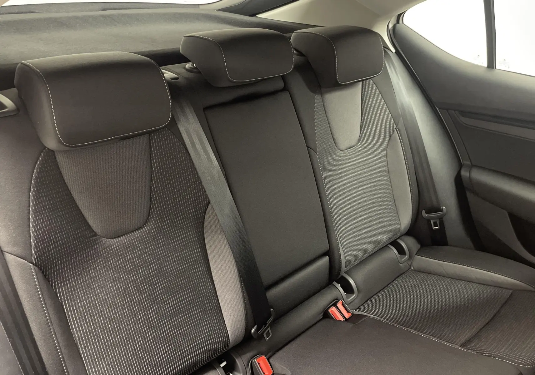 Vue intérieure sur les sièges arrière noirs avec appuie-têtes et ceintures de sécurité d'une Skoda Octavia 2024.