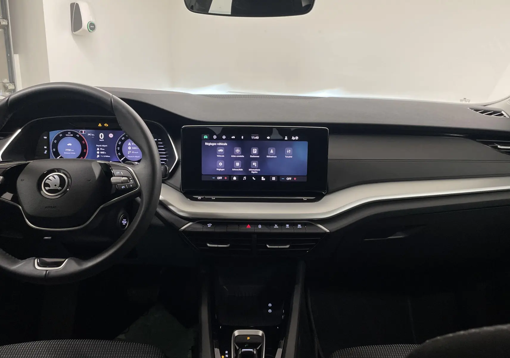 Intérieur de la Skoda Octavia 2024 blanc candy, vue frontale du tableau de bord avec écran tactile et volant multifonction.