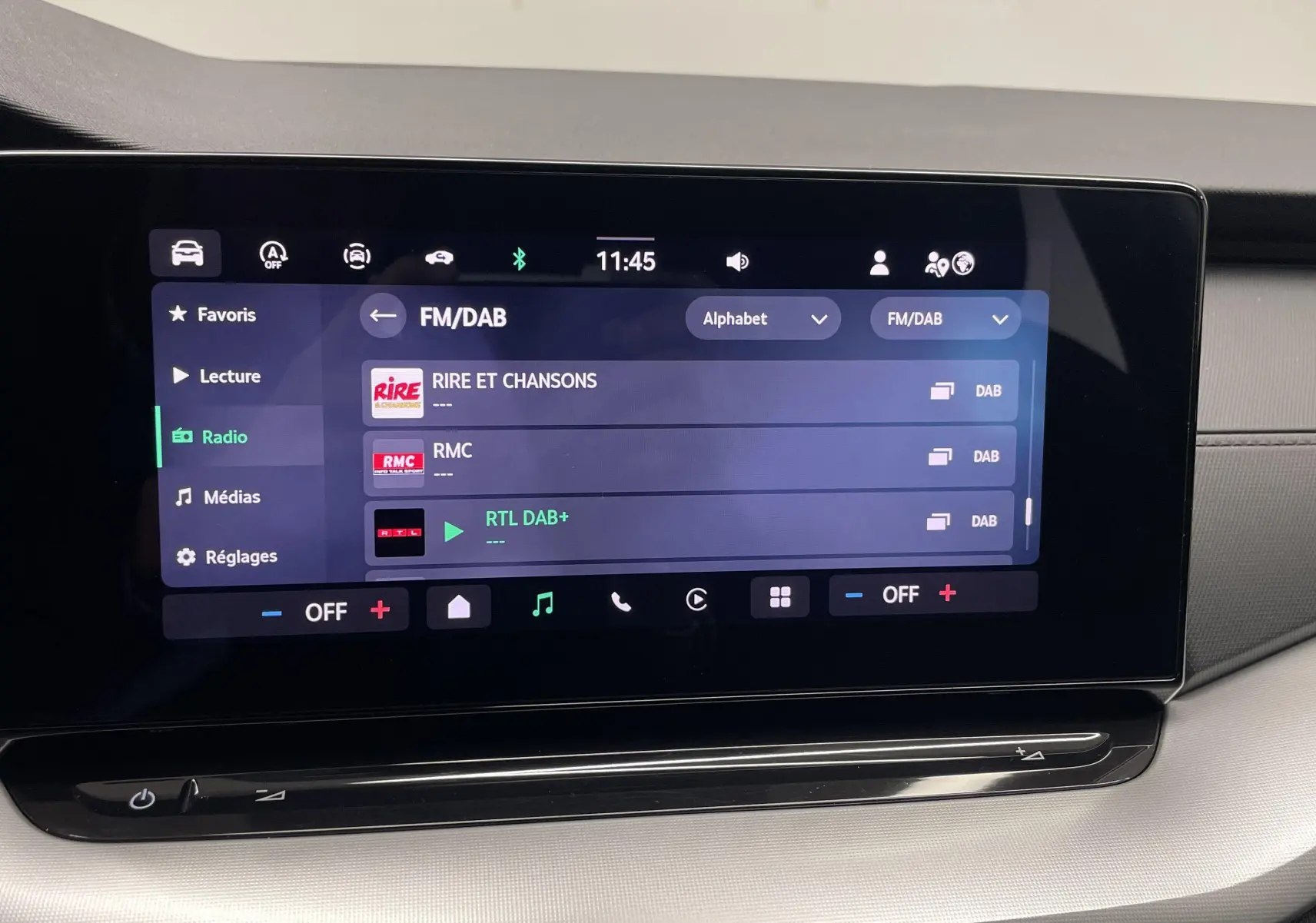 Écran tactile central du tableau de bord de la Skoda Octavia 2024 blanc candy, affichant les stations radio FM/DAB.