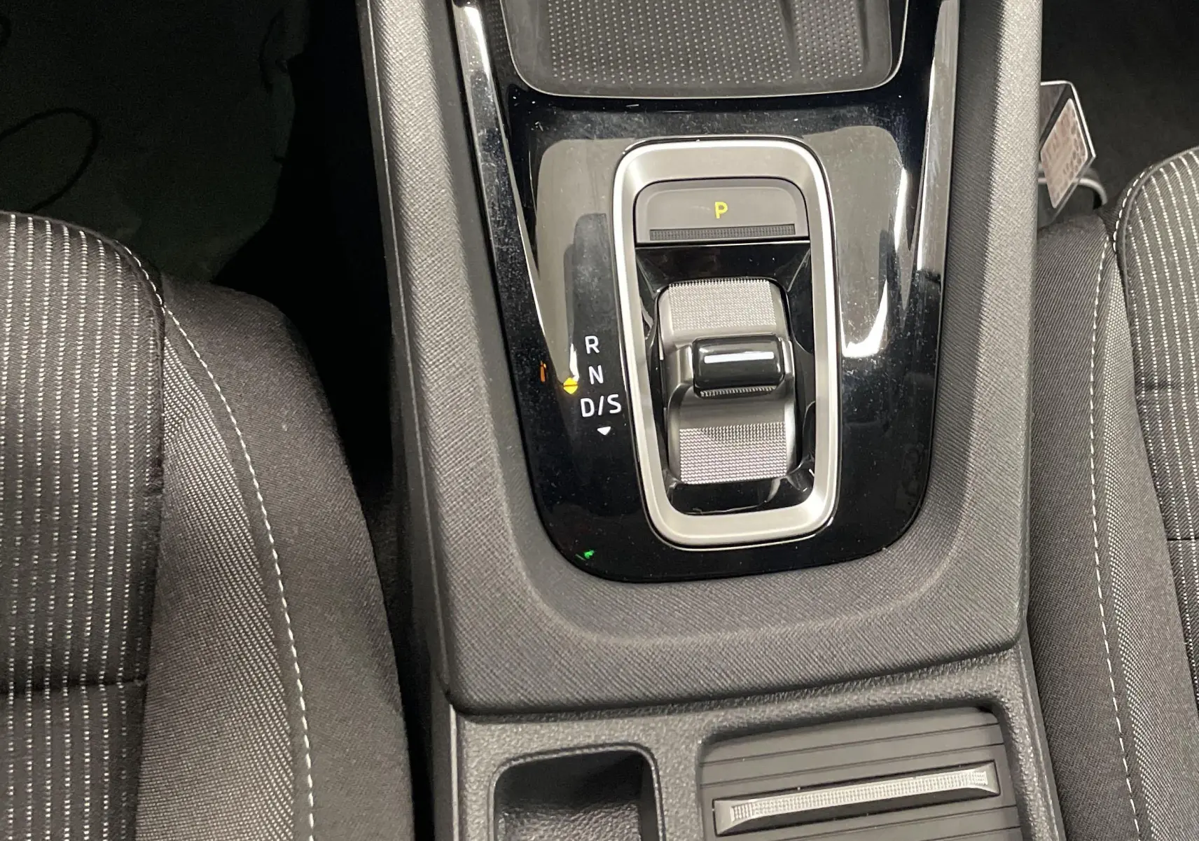Vue rapprochée de la console centrale de la Skoda Octavia 2024, avec levier de vitesses automatique et sièges tissu gris.