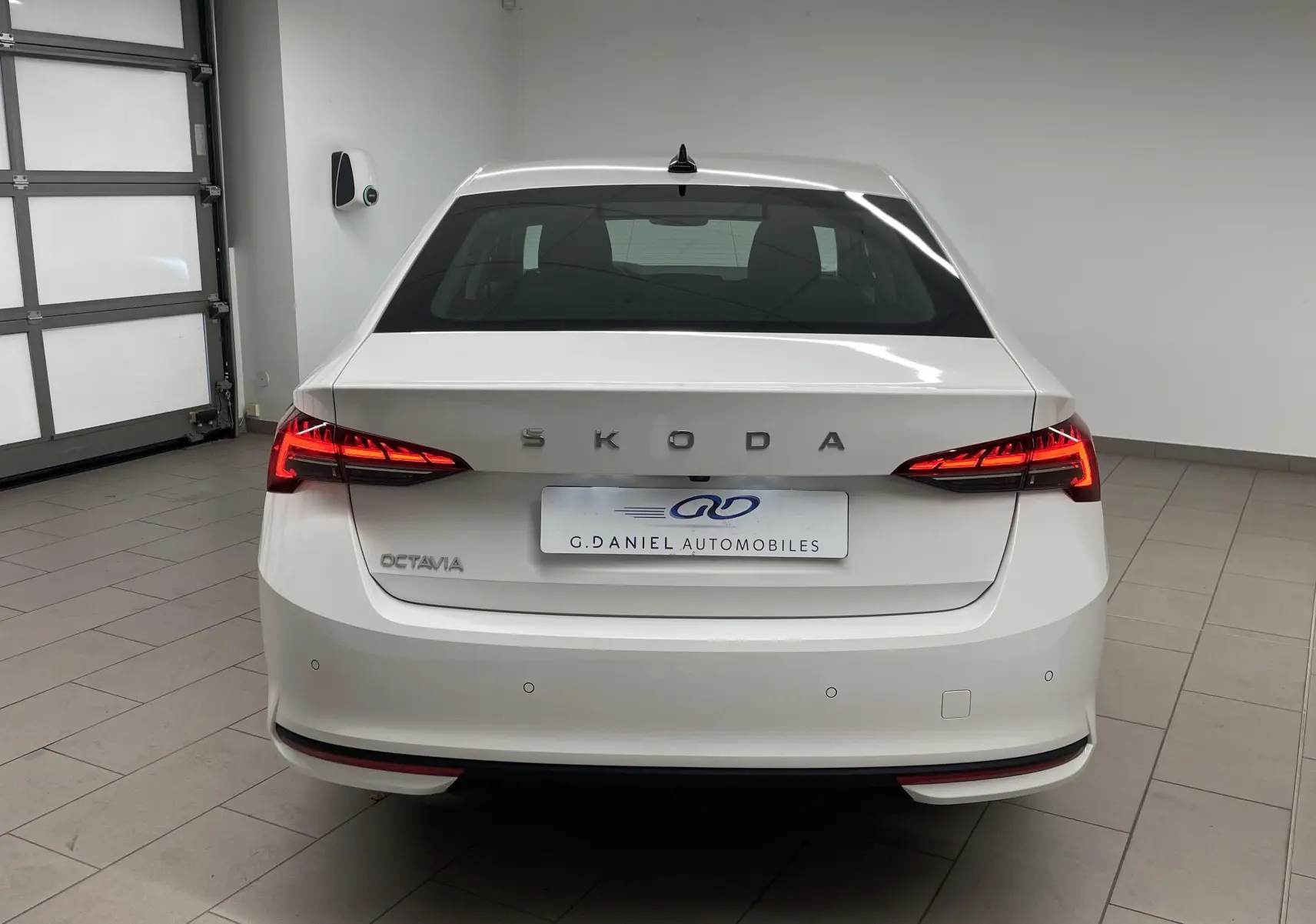 Vue arrière d'une Skoda Octavia blanche Candy 2024 avec feux LED allumés dans un garage intérieur.